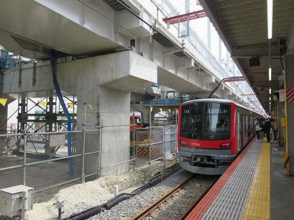 竹ノ塚駅ホーム横で建設中の高架橋と東武70000系電車